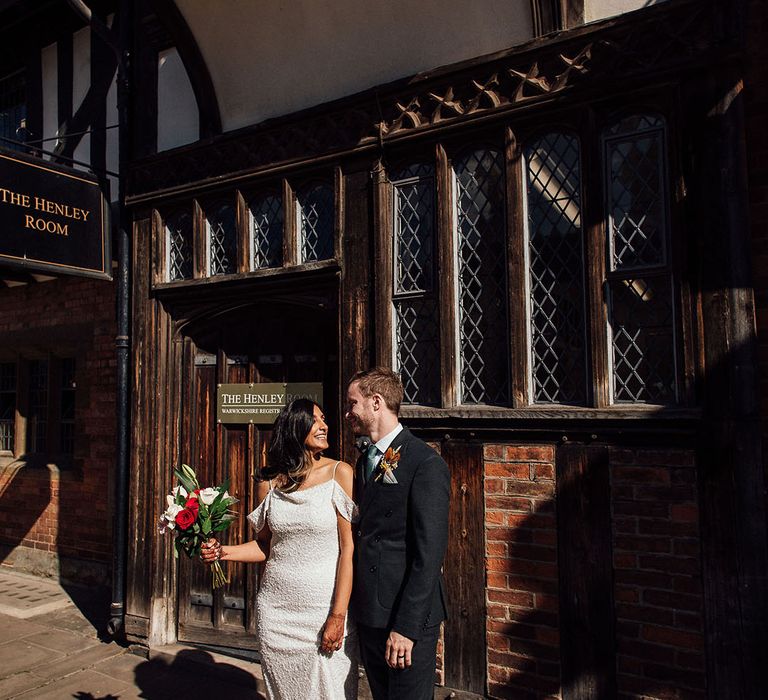 Bride in sequin embellished wedding dress stands beside her groom after civil ceremony 