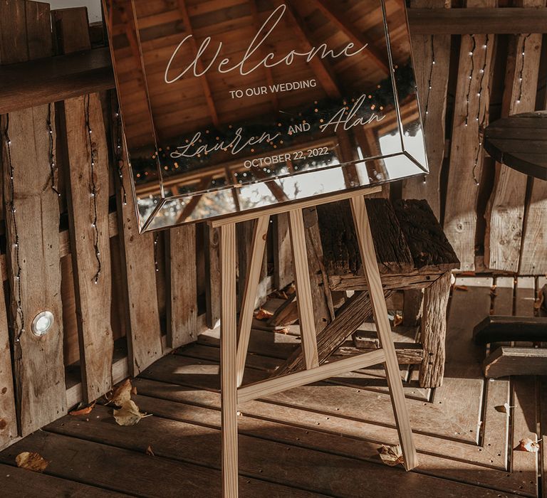 Mirror welcome wedding sign resting on a wooden easel 