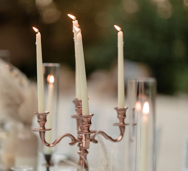 Rose gold candelabras line wooden banquet tables 