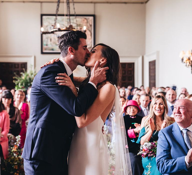 Bride in a Kyha wedding dress shares her first kiss with the groom as a married couple at Elmore Court 