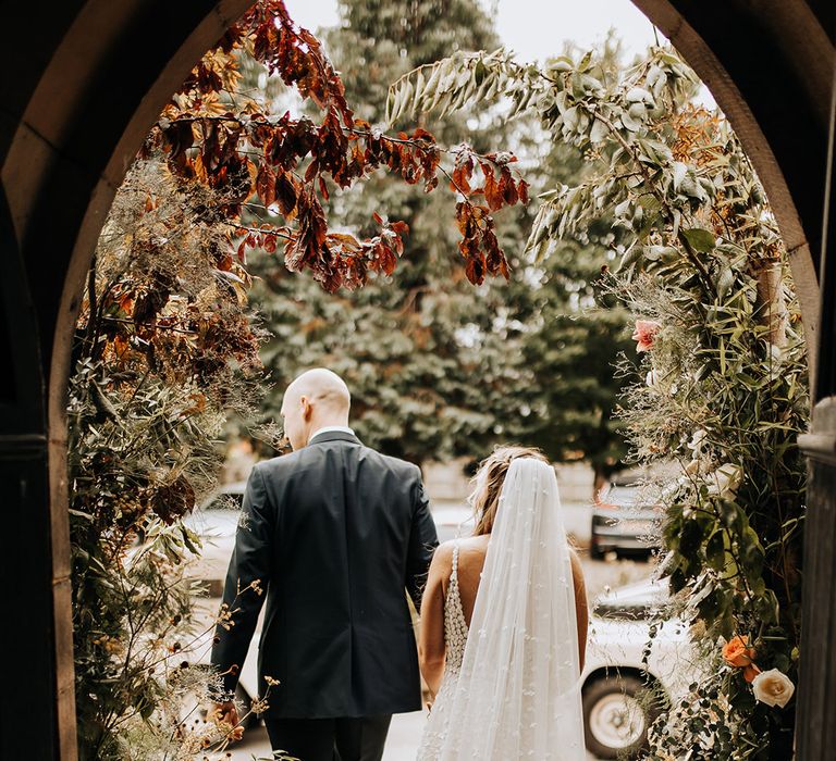 The groom exits the church with the bride wearing a long train dress and matching cathedral length veil 