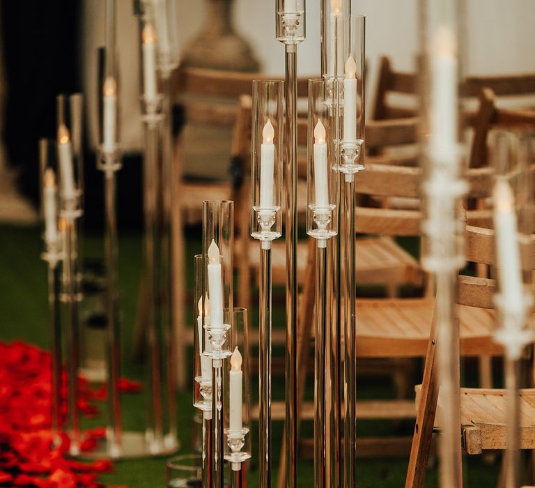 Red rose petals border the black carpet for the aisle with crystal candle displays for modern gothic romantic wedding 