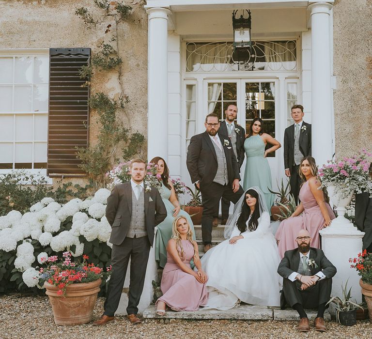 The wedding party at Preston Court with the bridesmaids in pastel pink and green wedding bridesmaid dresses and the groom and groomsmen wearing matching suits with pink and green ties with the bride