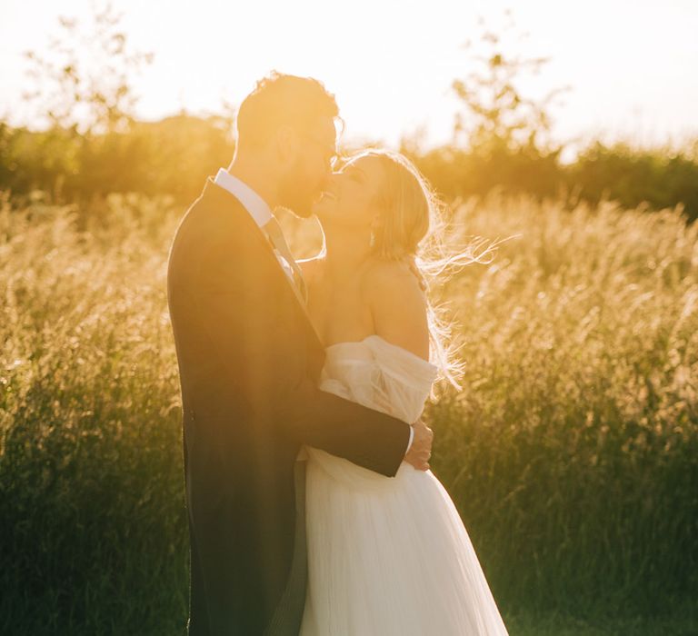 Golden hour couple portrait of the bride in a tulle wedding dress and groom in morning suit 