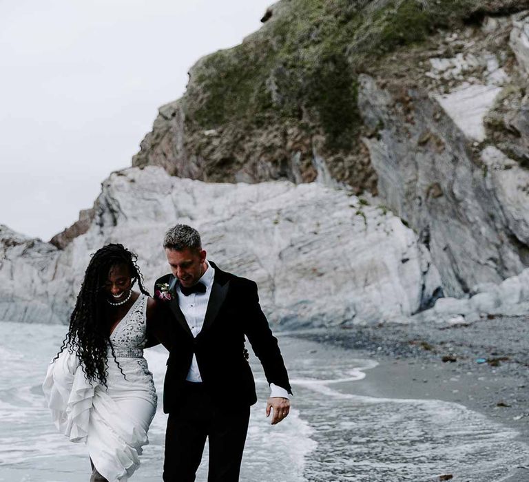 Bride and groom walking in the sea on Tunnels Beaches Devon wedding venue