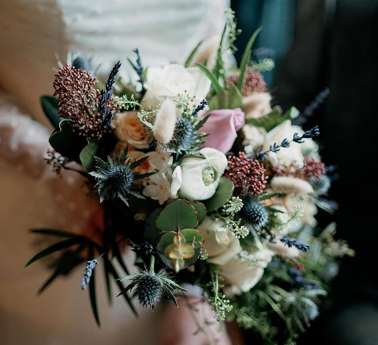 Wildflower wedding theme with the bride holding a small round bouquet of wildflowers 