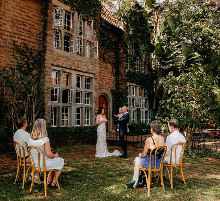 Bride and groom standing in front of their very small guest list at intimate elopement ceremony at Giraffe Manor wedding venue in Kenya, East Africa 