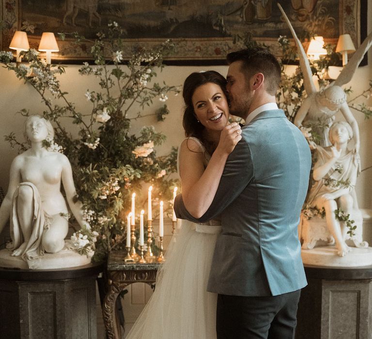 Bride in tulle wedding dress with groom in blue velvet blazer at their cosy intimate wedding ceremony 