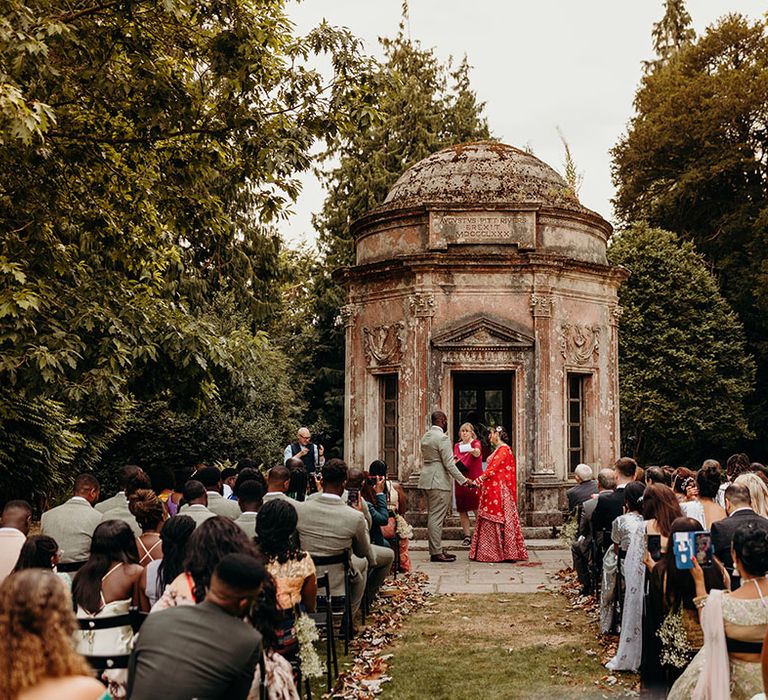 The bride and groom stand together for their fusion outdoor wedding ceremony 