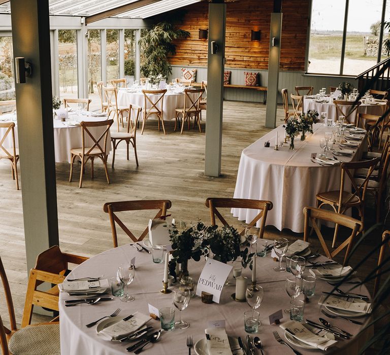 Stone Barn Cotswolds wedding venue decorated with round tables with white flower table centrepieces, table name signs and more 