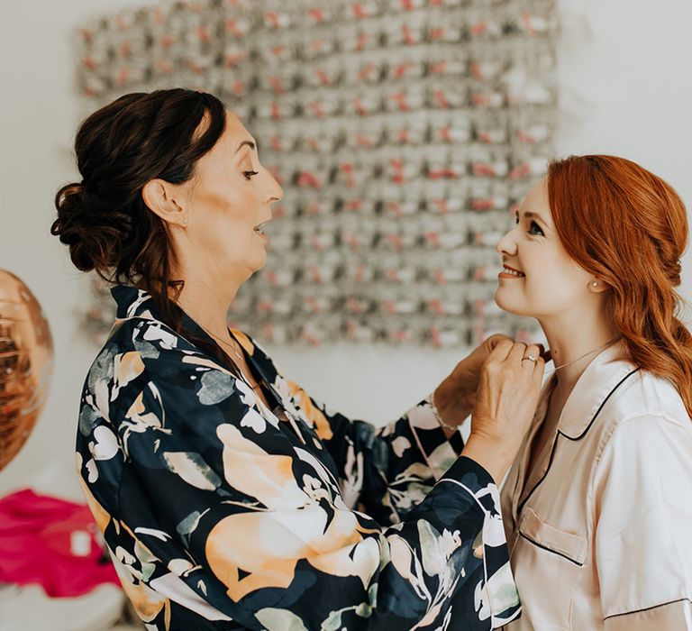 Mother of the bride in floral robe helps the bride get ready for the wedding day 