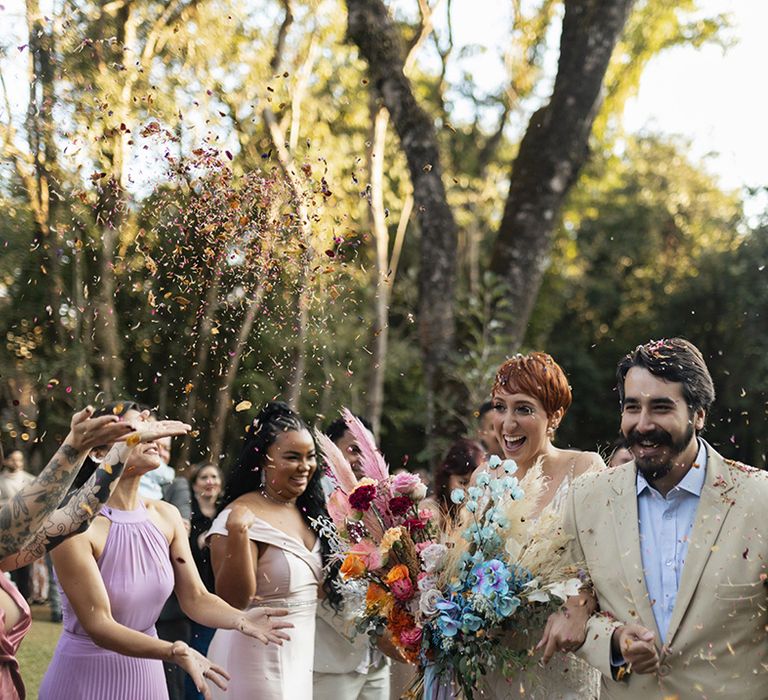 Confetti exit for couple at their outdoor destination wedding with guests throwing dried flowers 