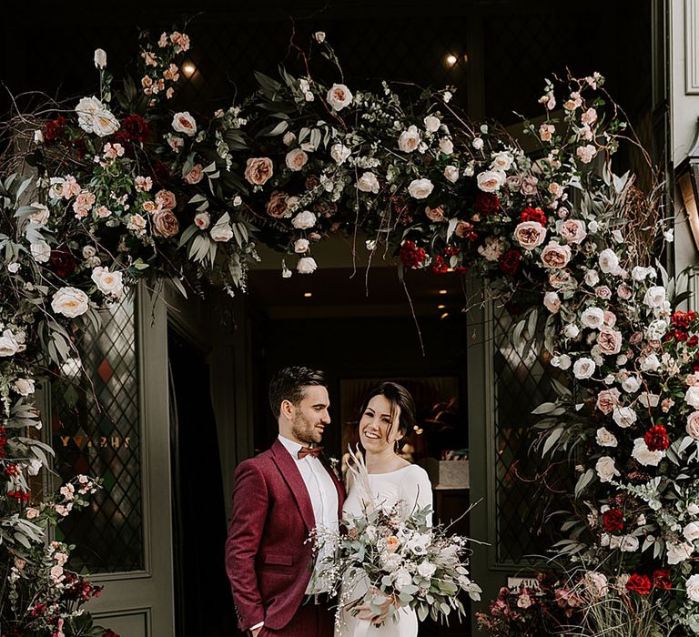 Red and pink rose flower arch decoration for bride and groom at winter wedding 