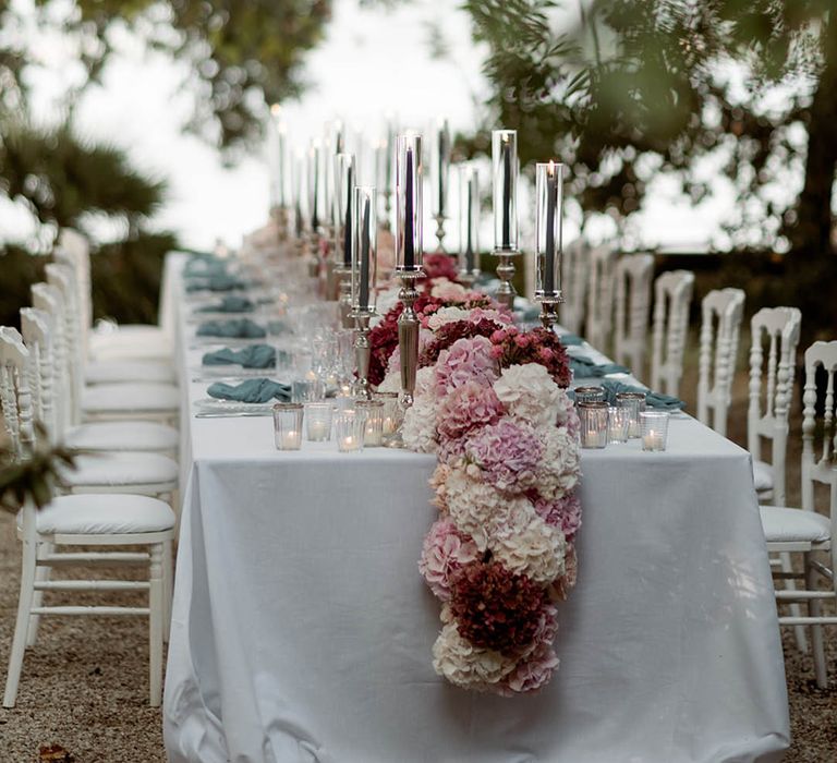 Tuscany outdoor al fresco wedding breakfast with chandeliers, pastel flowers and blue napkins 