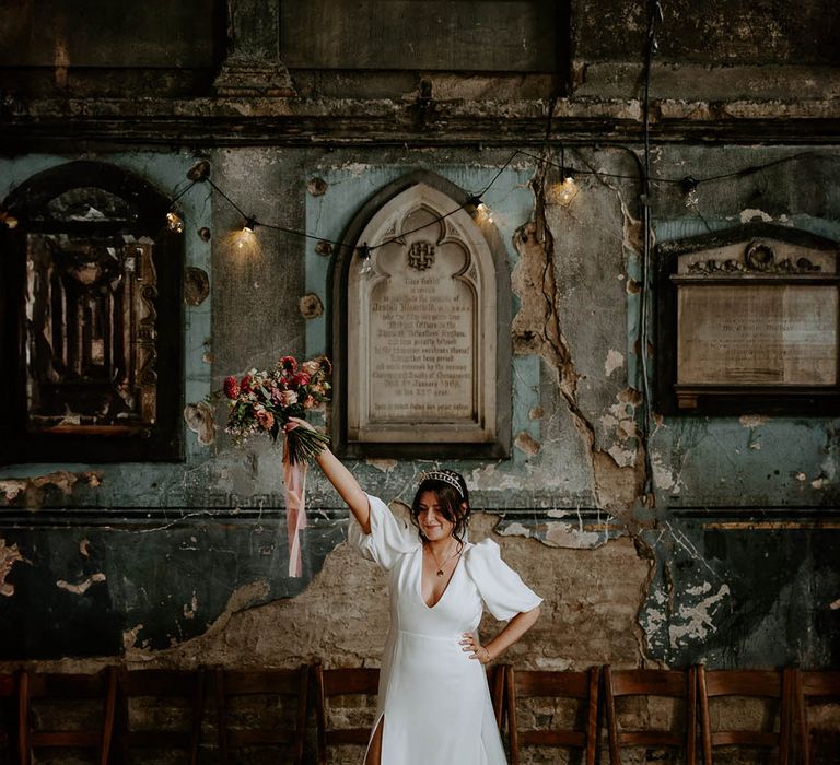 Bride wearing Halo and Wren wedding dress with puff sleeves and front slit holding bouquet 