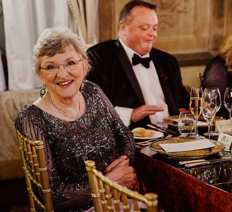 Mother of the bride in grey sparkly sequin dress sitting at the wedding breakfast 