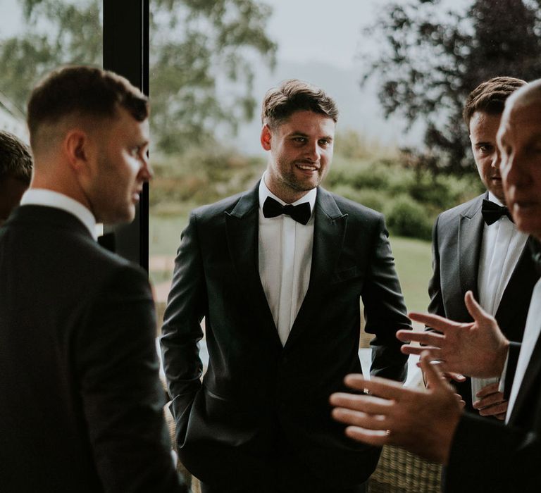 Groom in black tuxedos talking with the groomsmen