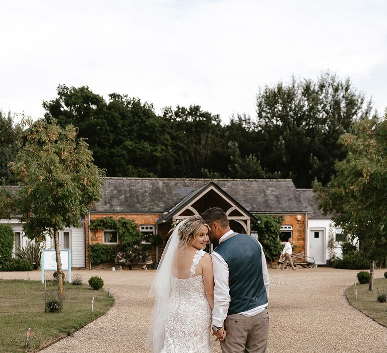 Bride in mermaid wedding dress with train smiling with the groom at Norfolk wedding 