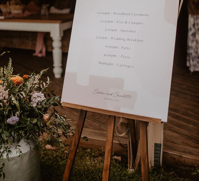 Pink and white wedding order of the day signage on easel 