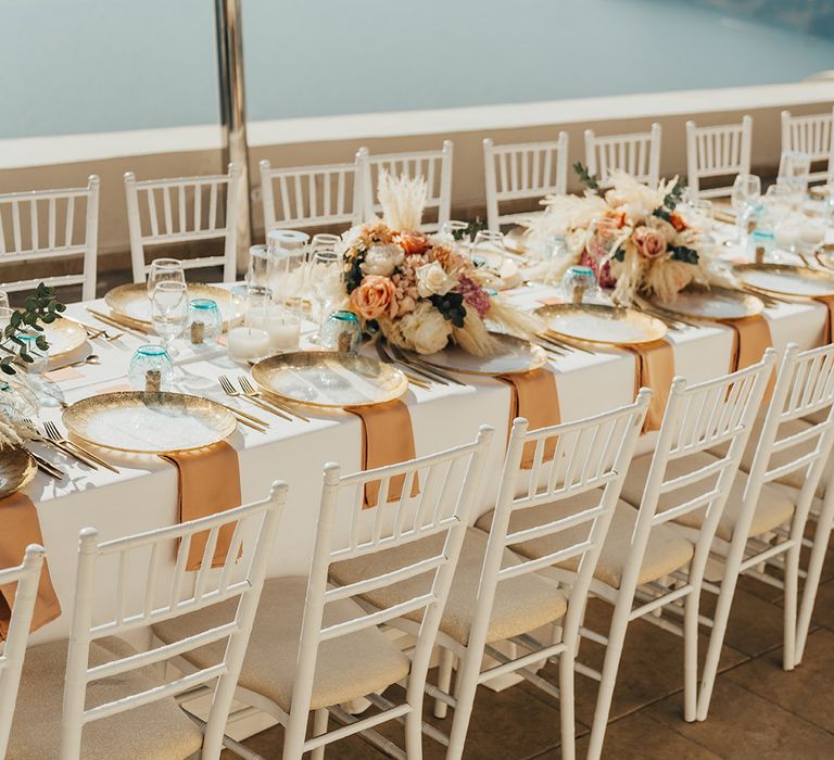 Boho wedding tablescape with boho pampas grass and coral flowers with gold and blue themed table decor 