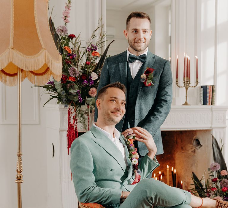 Grooms posing together on vintage armchair at French chateau wedding 