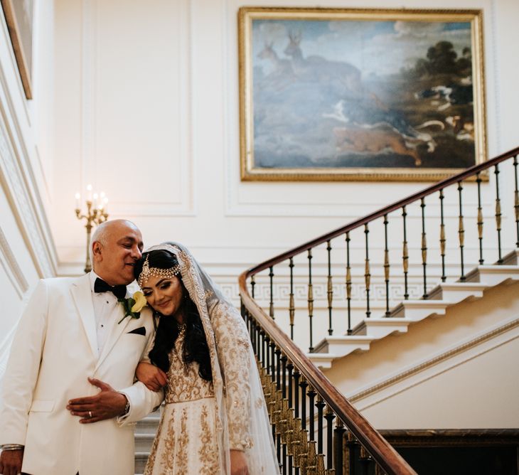 Father of the bride in white tuxedo kissing his daughter