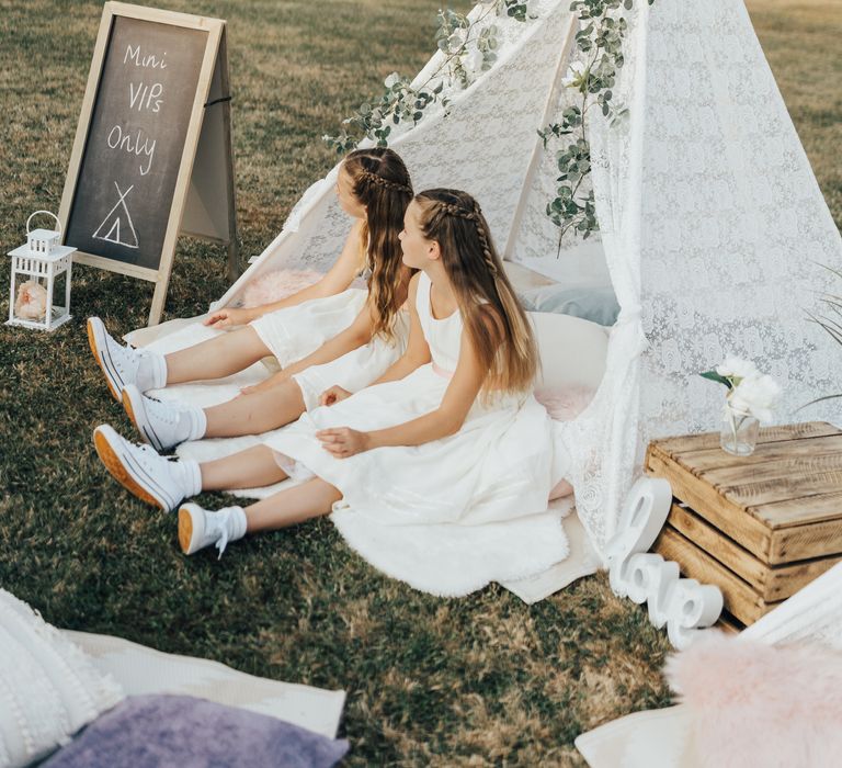 Small lace teepee for young wedding guests with blackboard and lanterns with foliage decor