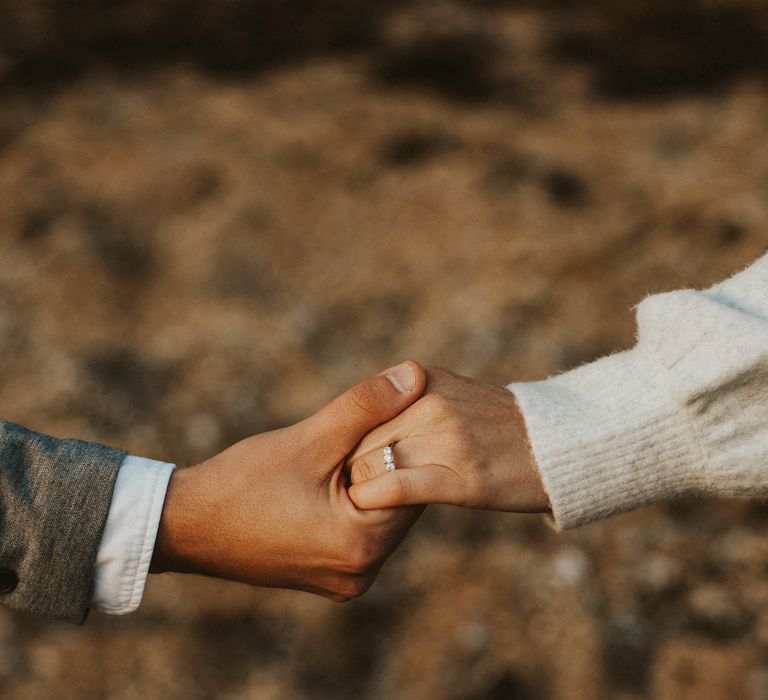 Bride and groom hold hands on engagement shoot