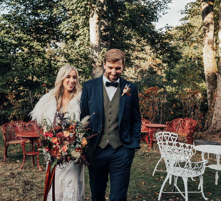 Blonde bride stands with groom wearing blue suit on wedding day 