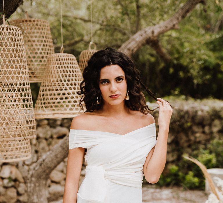 Bride stands outside wearing white boho gown