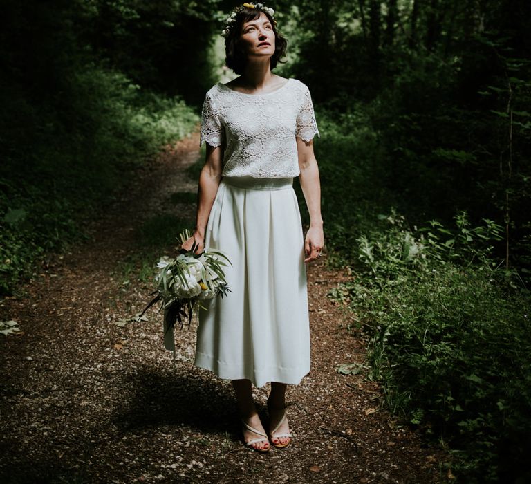 Dark short haired bride wears flower crown and white short sleeved lace wedding gown