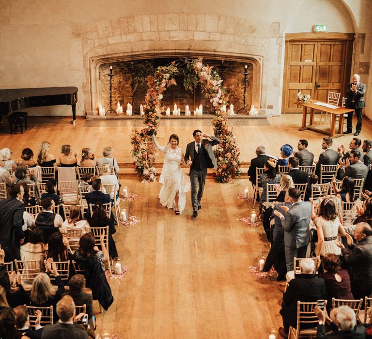 Dartington Hall, Devon wedding ceremony with giant fireplace and pillar candles, plus an autumn flower arch altar 