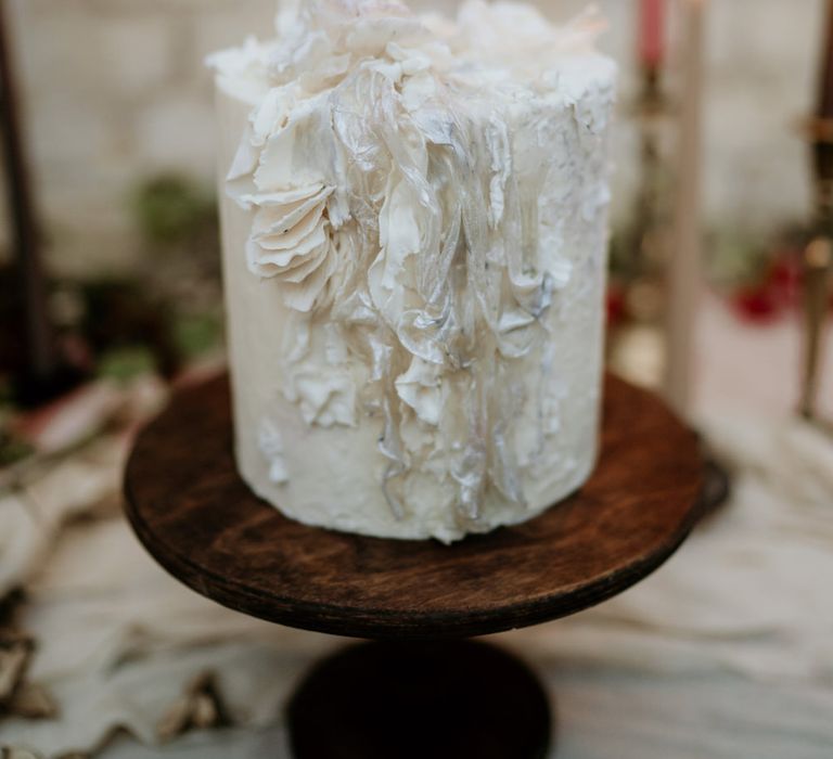 single tier wedding cake with intricate design on a wooden cake stand 