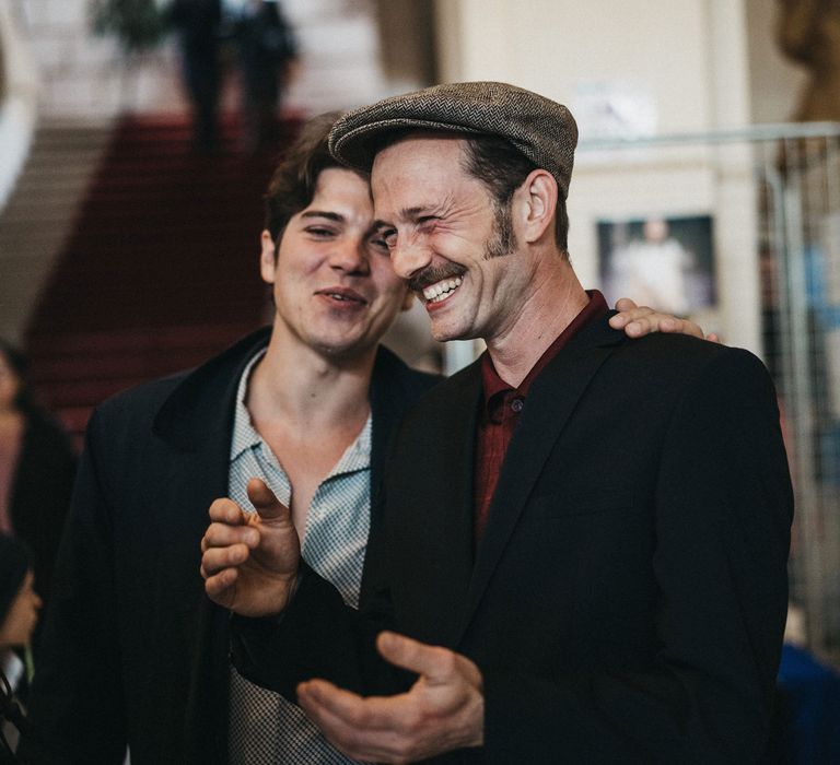 Franco American groom in a red shirt, black suit and flat cap 