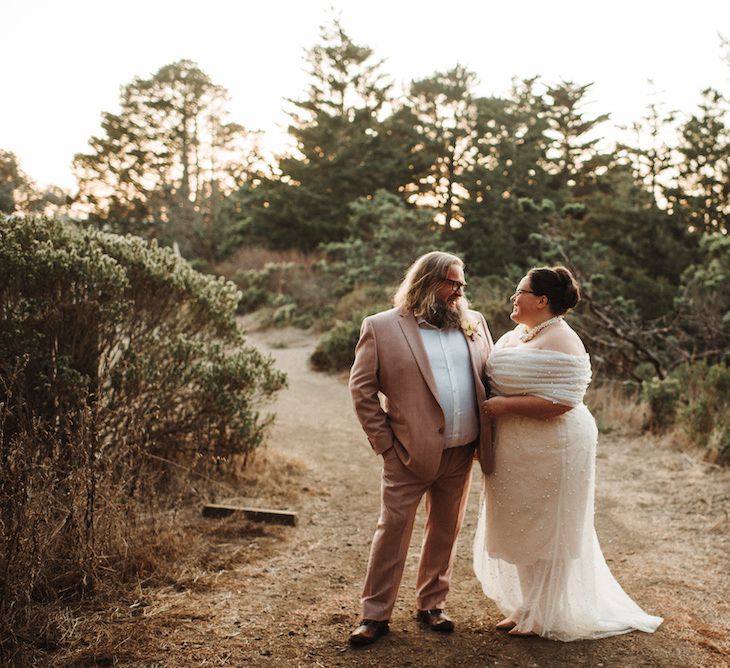 Bride and groom portrait with the groom in a pink suit and the bride in a strapless wedding dress with layered tulle detail