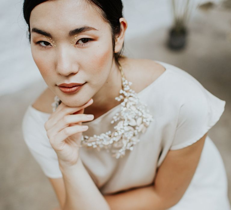 The bride wore minimal gold foil eye makeup for a white and gold wedding theme