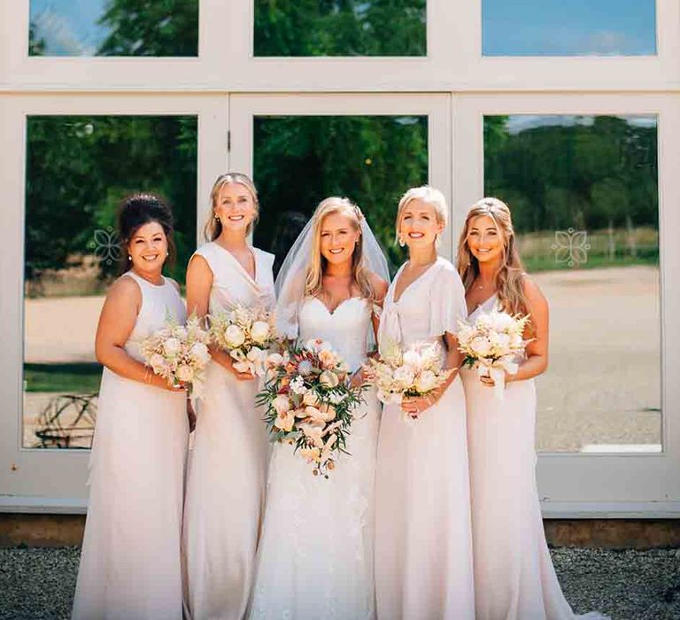 Bridal party outside barn wedding with bride wearing pink bridesmaid dresses