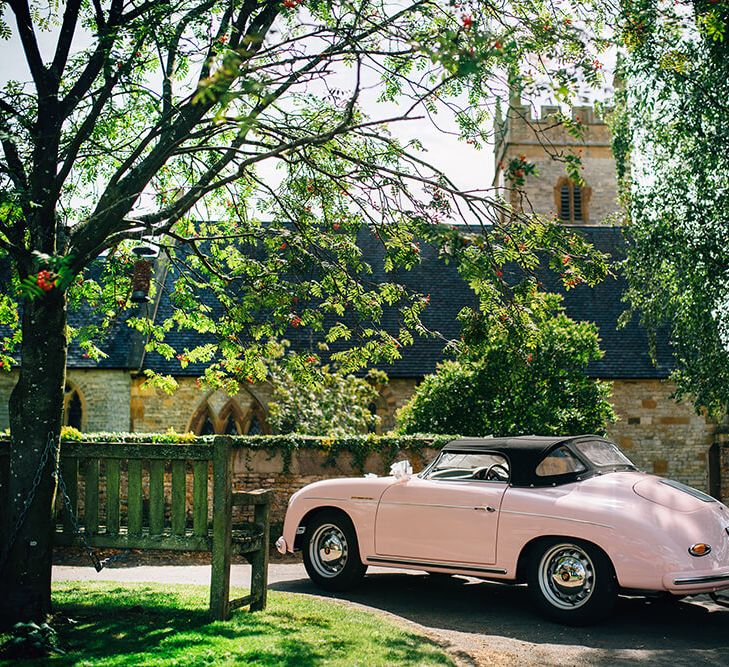 Pale pink porsche outside church wedding in Warwickshire