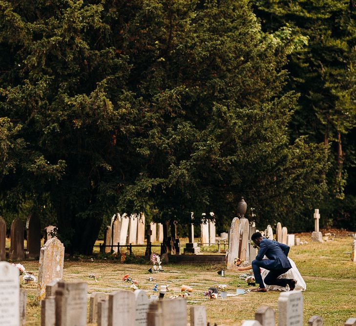 Bride and groom laying flowers on a grave at their church wedding 