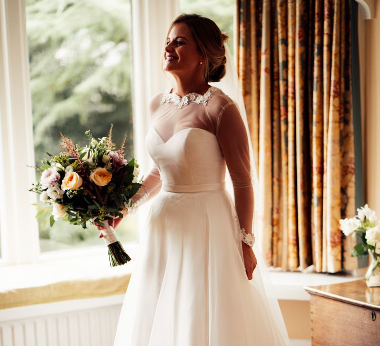 Bride laughs on wedding day stood in bay window