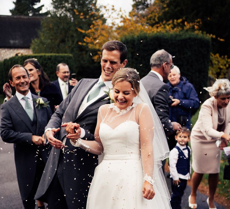 Bride & groom walk through confetti being thrown on wedding day