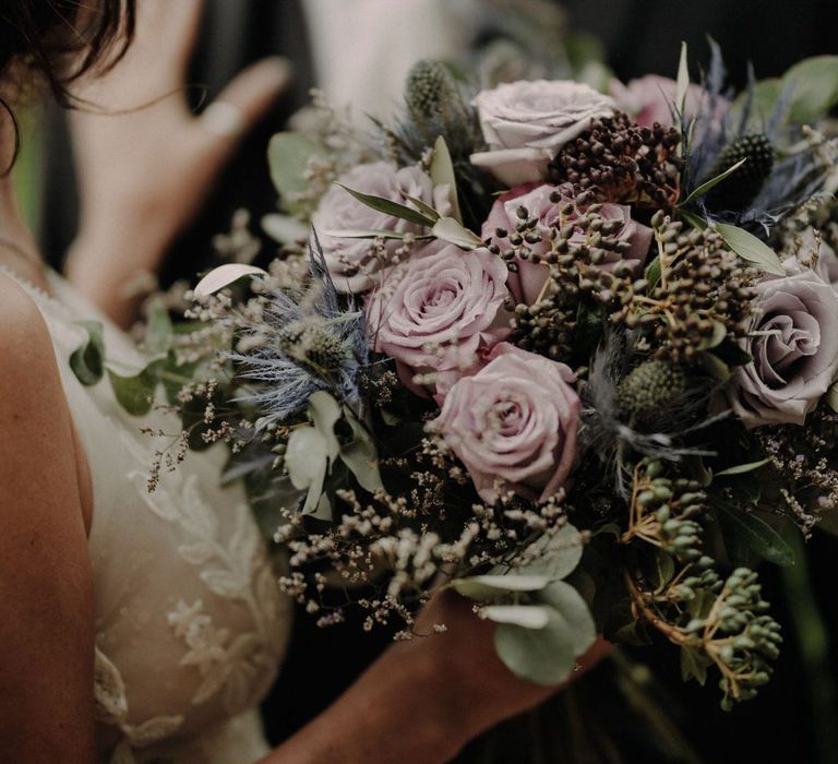 A bouquet of purple roses, thistles and wild flowers