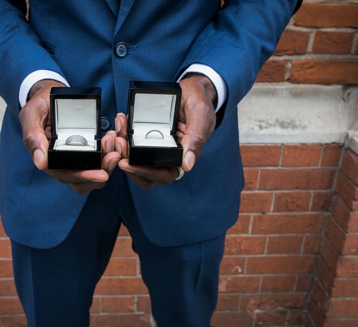 Best man in a navy suit holding the wedding ring boxes 