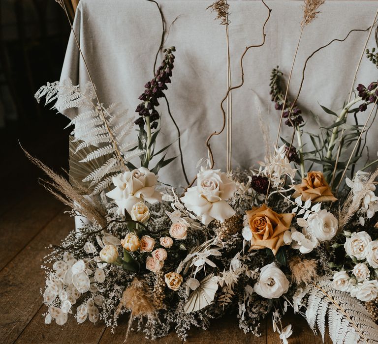 Dried and fresh flower arrangements with twisted willow and frilly caramel-toned garden roses