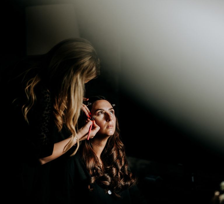 Bride with long brown curled hair gets make up done at Hotel du Vin Harrogate before Harrogate wedding