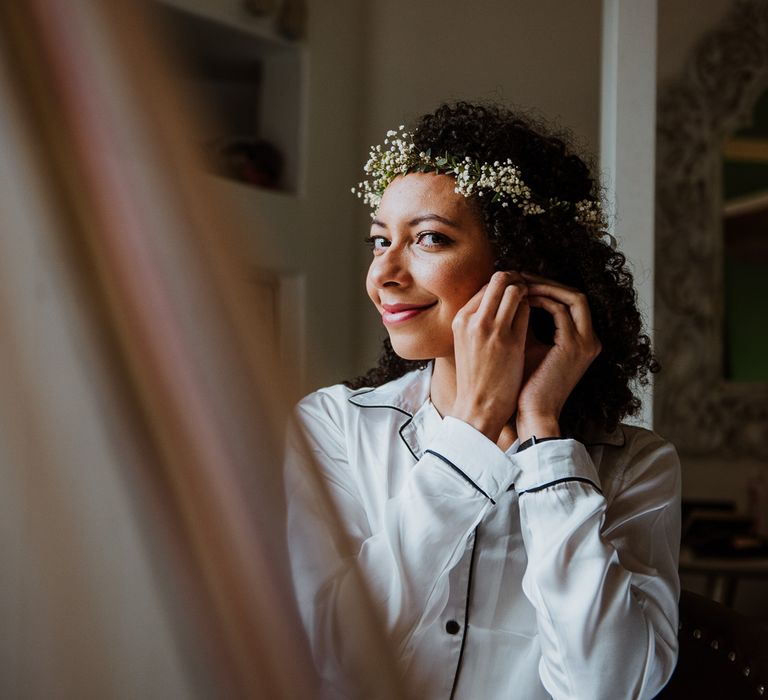 Bride applies her earrings on the day of her wedding 