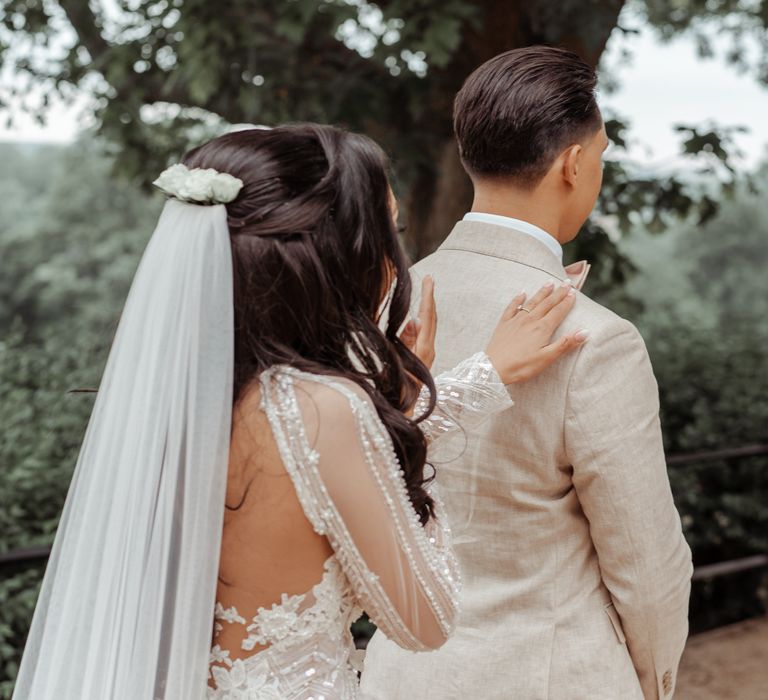 Bride moves in for first look moment as she places her hand on grooms shoulder