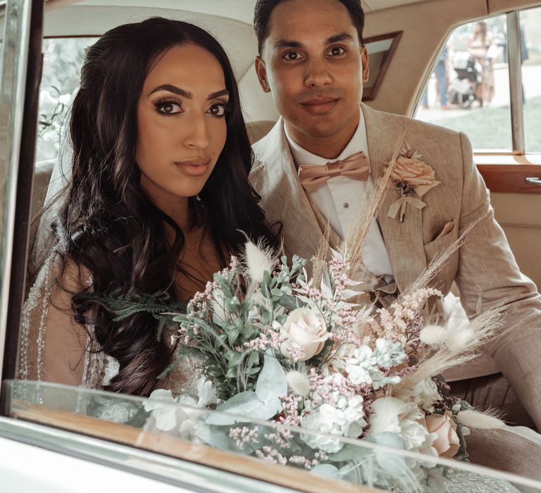 Bride & groom sit within wedding car on their wedding day