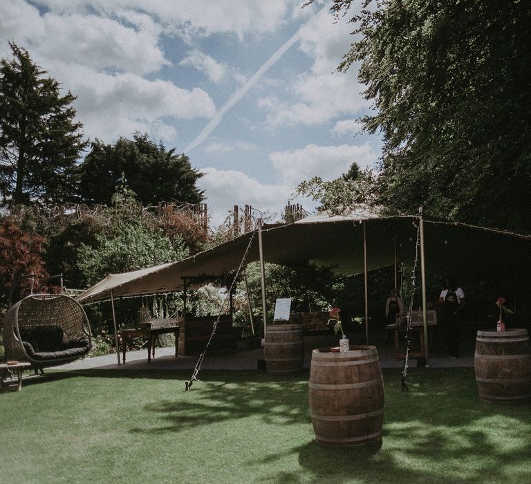 Garden wedding reception with tipi, fair lights, barrels and bar for boho wedding