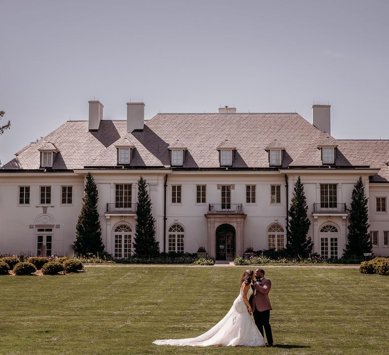 Bride & groom stand within the grounds of the BASH wedding venue set in lush green gardens